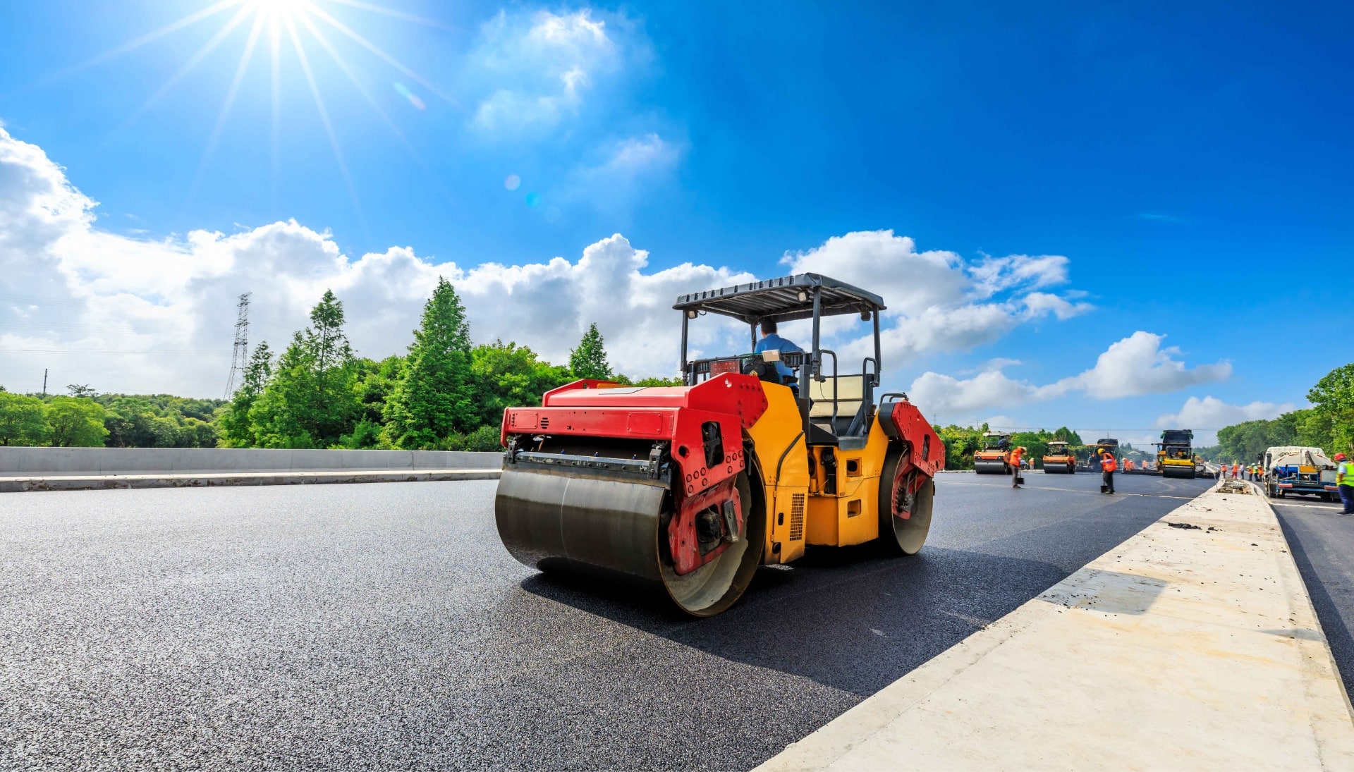 A team of construction workers operating heavy machinery, meticulously laying down fresh, smooth asphalt on a newly constructed road in Durham, with steam rising from the hot surface.
